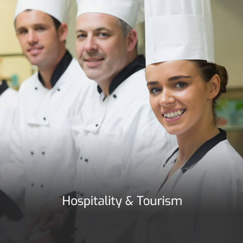 Three culinary professionals in white coats and chefs' hats stand in a line.