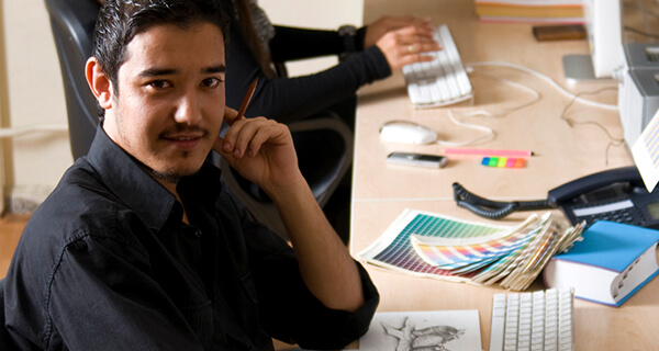 A man sits at his desk while working on his latest sketch drawing.