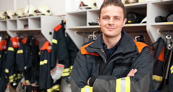 A young public safety professional stands proud in his firefighter uniform.