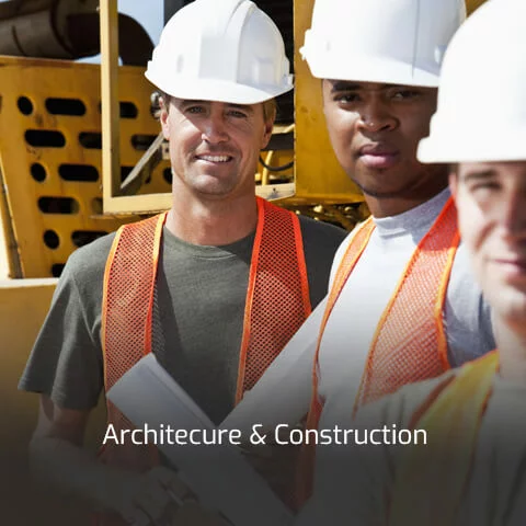 Three men in construction hats and orange vests stand next to construction machinery.