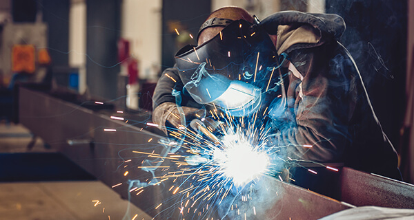 Sparks fly around a manufacturing professional as he works on a project.