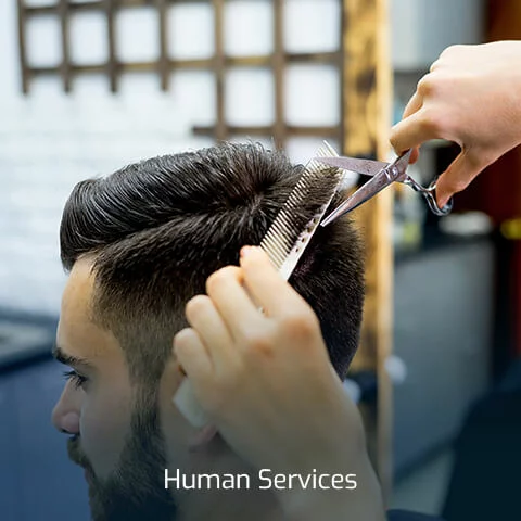 A man getting a haircut from a student in the Human Services program.